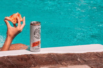 BevAlc trends hard seltzers drinking whiteclaw by pool with pizza in hand